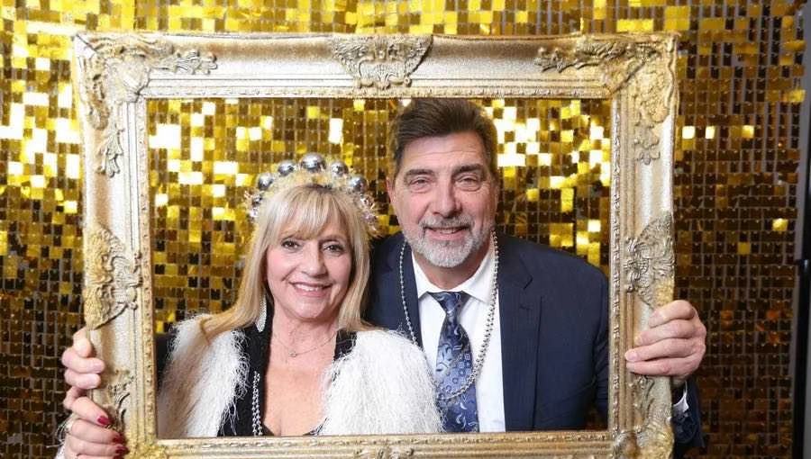 A couple posing with a gold frame at a past gala